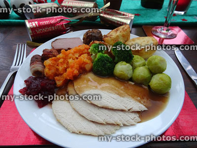 Stock image of Christmas dinner on dining table with roast turkey, crackers