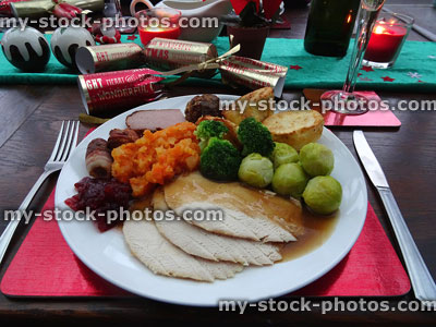 Stock image of Christmas dinner on red placemat, turkey, vegetables, crackers