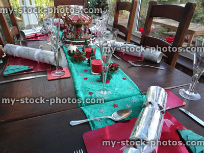 Stock image of green-velvet table runner with Christmas decorations, crackers, wine-glasses