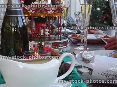 Stock image of Christmas dinner table decorations, carousel, crackers, gravy-boat, sparkling-wine