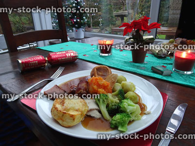Stock image of Christmas dinner table runner with crackers, candles, poinsettias