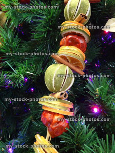 Stock image of Christmas tree decorations, fairy lights, dried fruit garland, cinnamon sticks