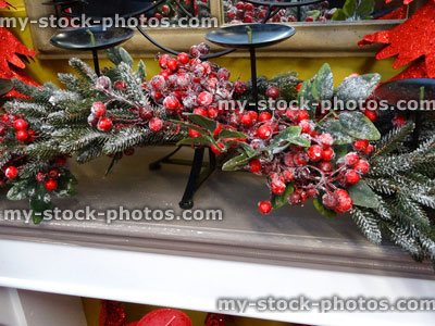 Stock image of stone fireplace, Christmas decorations, artificial garland, berries, candlesticks