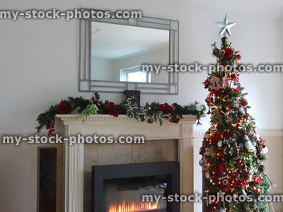 Stock image of artificial Christmas tree, garland and modern gas fireplace