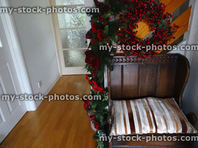 Stock image of hallway decorated with wreath and garland, wooden settle seat