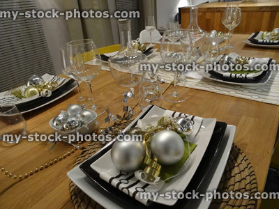 Stock image of black and white Christmas table setting, crockery / plates, napkins, silver baubles, decorations, wine glasses