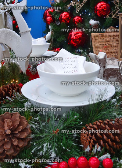 Stock image of artificial wreaths on Christmas dining table, white crockery