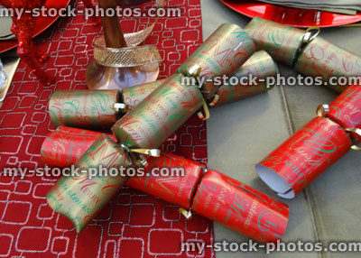Stock image of Christmas dinner table setting, decorative table cloth runner, crockery / plates, crackers, ornaments, ribbon