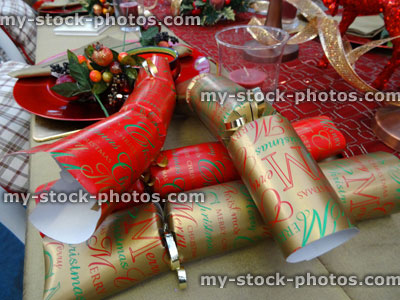 Stock image of Christmas dinner table setting, decorative table cloth runner, crockery / plates, crackers, gold ribbon