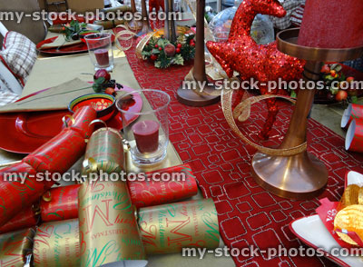 Stock image of Christmas dinner table setting, table cloth runner, crockery / plates, crackers, red candles, decorations