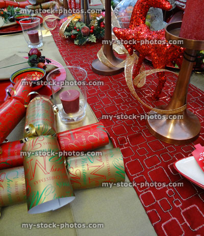 Stock image of Christmas dinner table setting, decorative table cloth runner, crockery / plates, crackers, red candles
