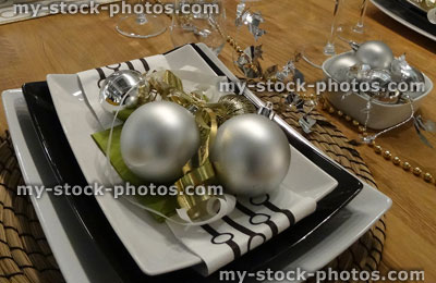 Stock image of black and white Christmas table setting, crockery / plates, napkins, silver baubles, decorations