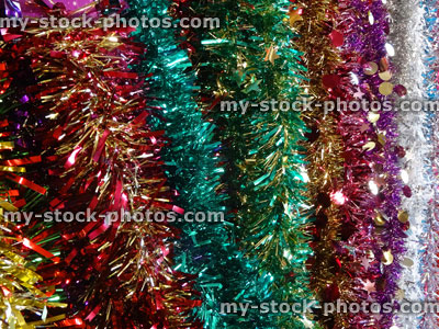 Stock image of tinsel Christmas decorations, red, pink, green, purple, silver, white, gold