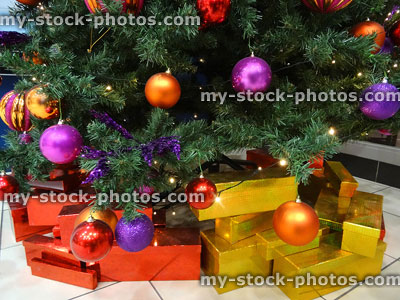 Stock image of red and gold wrapped presents beneath Christmas tree