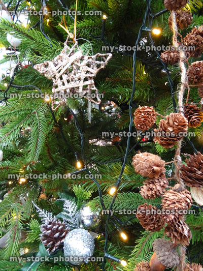 Stock image of artificial Christmas tree decorations, pine cones string, wicker silver stars, baubles