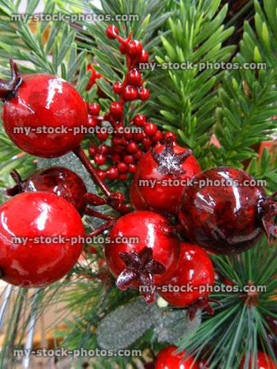 Stock image of artificial Christmas tree decorations, plastic red holly berries, conifer foliage / spruce needles