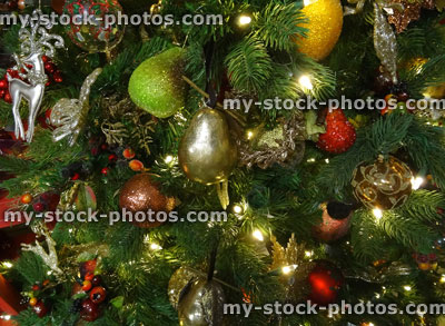 Stock image of artificial Christmas tree, gold / silver decorations, glitter, fruit, baubles, apples pears