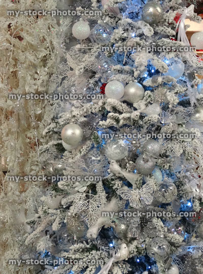 Stock image of artificial Christmas tree, white / silver decorations, glitter, birds, butterflies, baubles