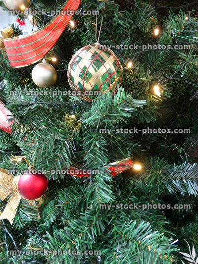 Stock image of artificial Christmas tree decorations, baubles, red and silver ribbons, fairy lights