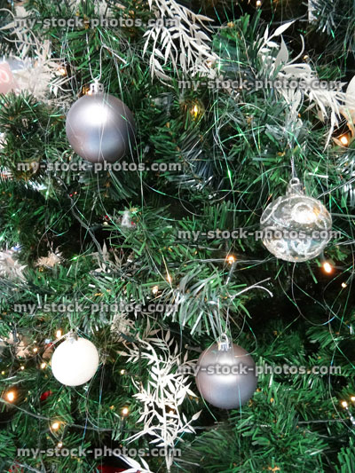 Stock image of artificial Christmas tree decorations, silver and white baubles, fairy lights