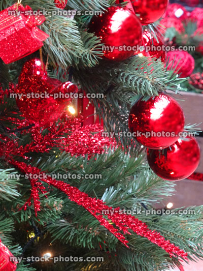 Stock image of artificial Christmas tree, red decorations, garlands, baubles, tinsel, parcels, fairy lights