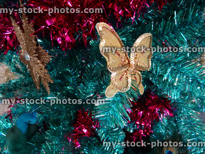 Stock image of tinsel Christmas tree, green / turquoise peacock, gold snowflakes, butterfly decorations