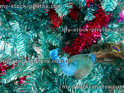 Stock image of tinsel Christmas tree, green / turquoise peacock decorations, glitter, red tinsel