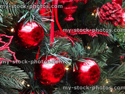 Stock image of artificial Christmas tree, red decorations, garlands, baubles, tinsel, parcels, fairy lights