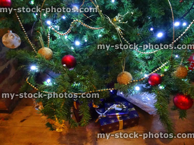 Stock image of artificial Christmas tree, red / gold decorations, baubles, chains, wrapped presents / gifts
