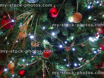 Stock image of artificial Christmas tree, red / gold decorations, glass baubles, plastic pearl chains / streamers