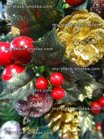 Stock image of artificial Christmas tree decorations, gold pine cones, berries, fruit, apple