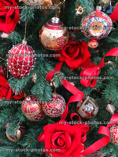 Stock image of artificial Christmas tree, red bow decorations, baubles, tinsel, berries, ribbons, roses