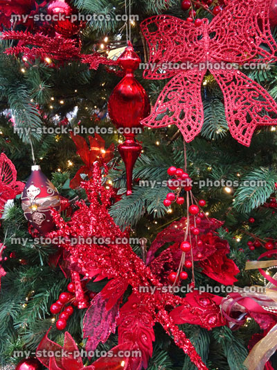 Stock image of artificial Christmas tree, red bow decorations, baubles, tinsel, berries, ribbons, roses