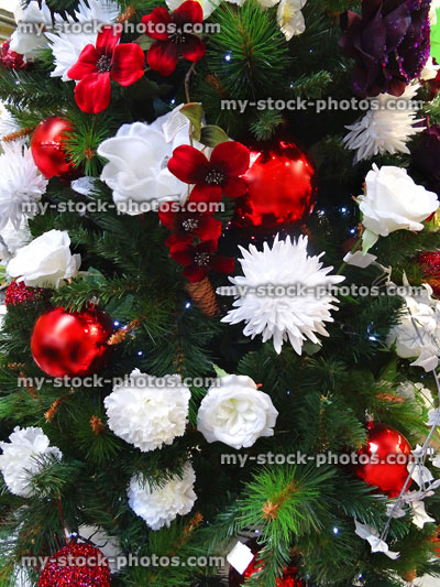 Stock image of artificial Christmas tree with red-and-white silk flowers / baubles