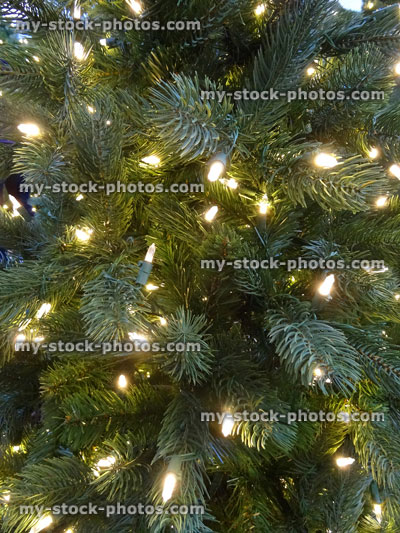 Stock image of artificial Christmas tree decorations, green foliage needles, white LED fairy lights