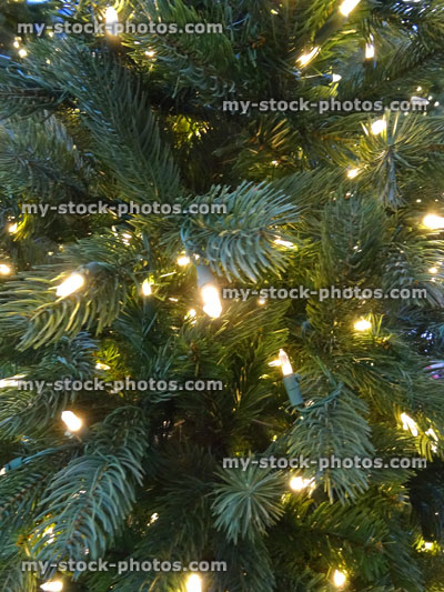 Stock image of artificial Christmas tree decorations, green foliage needles, white LED fairy lights