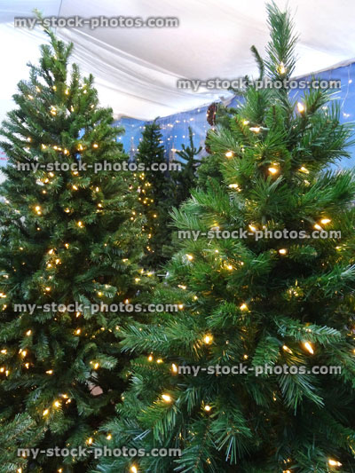 Stock image of artificial Christmas trees / decorations, green foliage needles, white LED fairy lights, banner