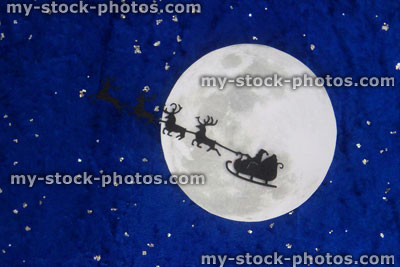Stock image of santa Claus / Father Christmas sleigh / reindeer silhouette flying, moon, starry sky night