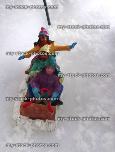 Stock image of model Christmas snow scene with miniature people sledging
