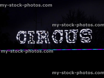 Stock image of illuminated circus sign, white lights, black night time dark sky