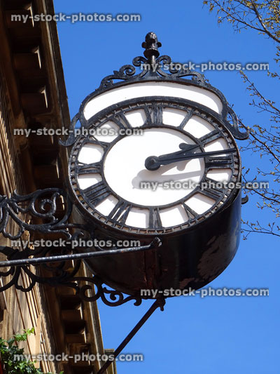 Stock image of outdoor metal wall clock hanging on shop wall