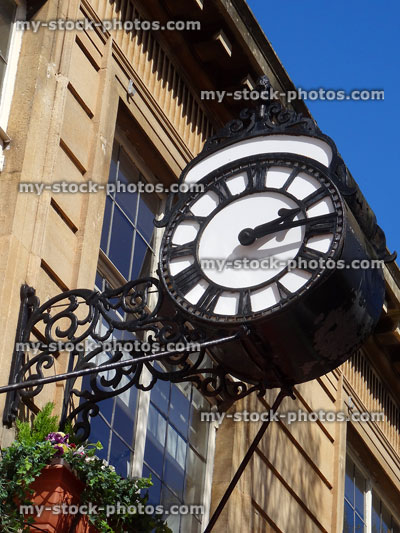 Stock image of metal wall clock above shop window, Roman numerals