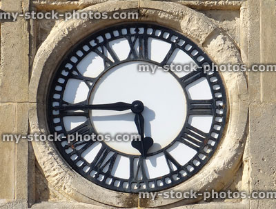 Stock image of sandstone clock with white clockface and Roman numerals