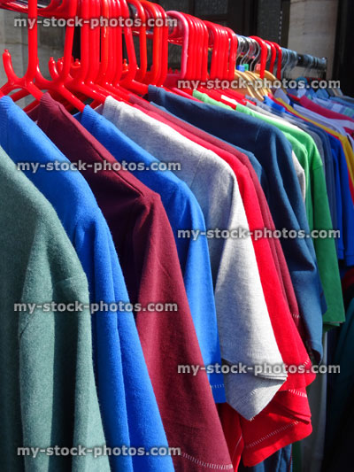 Stock image of coloured T shirts hanging on clothes rail outside shop