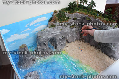 Stock image of school homework project, painting cliffs grey with paintbrush