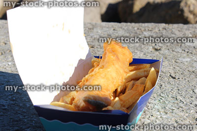 Stock image of greasy cod fish and chips being eaten outside