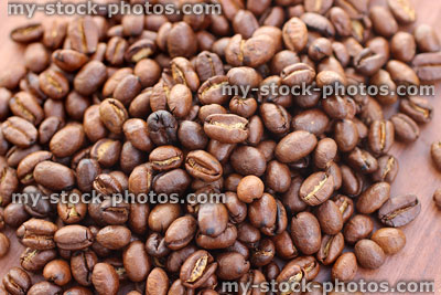 Stock image of roasted coffee beans on wooden breadboard, for grinding