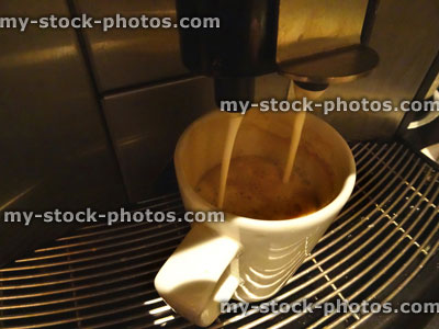 Stock image of stainless steel coffee machine making cup of frothy cappuccino