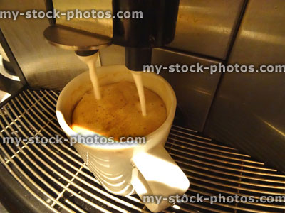 Stock image of stainless steel coffee machine making mug of frothy cappuccino