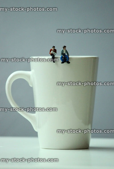 Stock image of coffee break with mini people sat on coffee mug